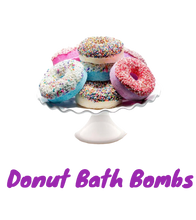 Load image into Gallery viewer, Colorful artisanal Donut Bath Bombs with sprinkles on a white cake stand, made with organic and eco-friendly ingredients for a relaxing bath experience